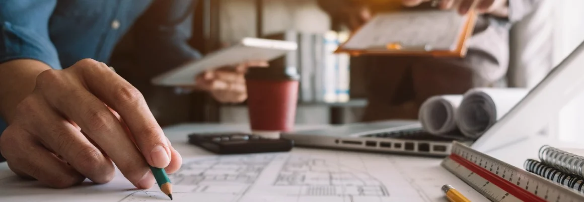 Person zeichnet auf Bauplan